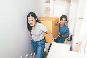 Young couple qualified for the First Home Buyer Choice and now is carrying a box to move in their new home
