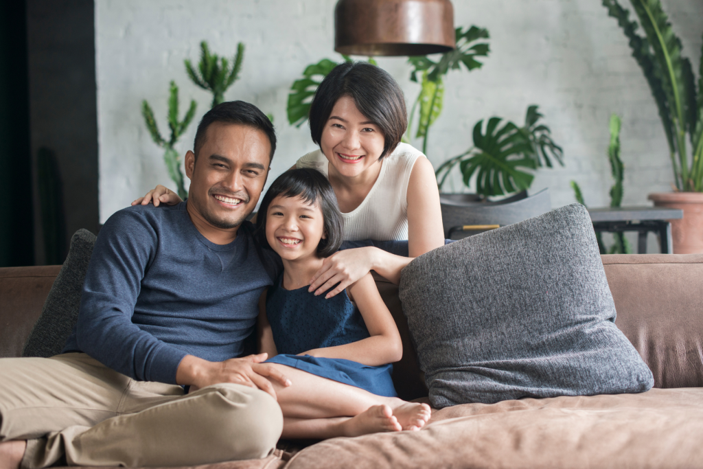 First home buyer Asian couple looking at the camera with their child looking happy to be in their new home