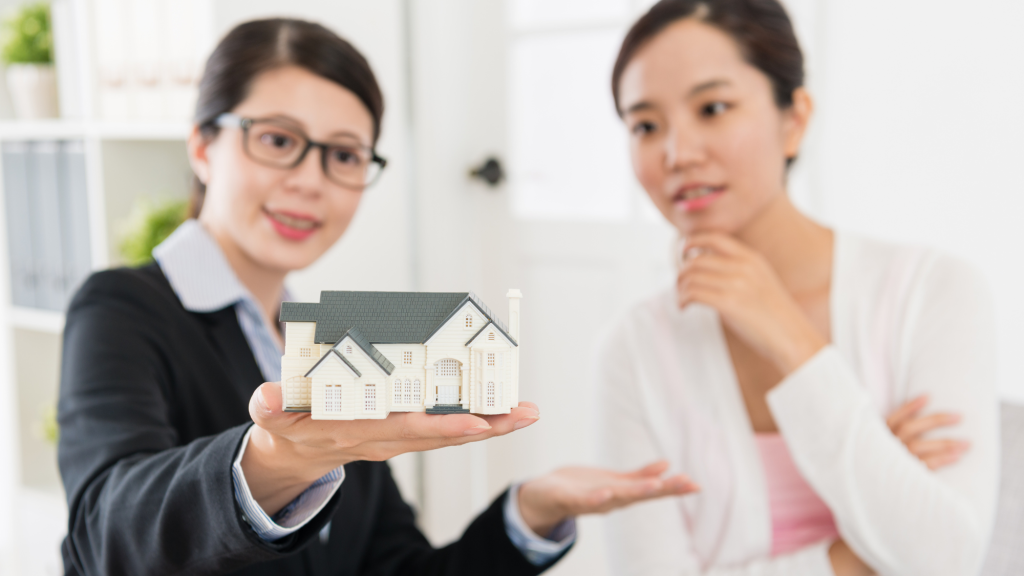 Mortgage broker presenting a miniature house model to a young property investor buying an investment property