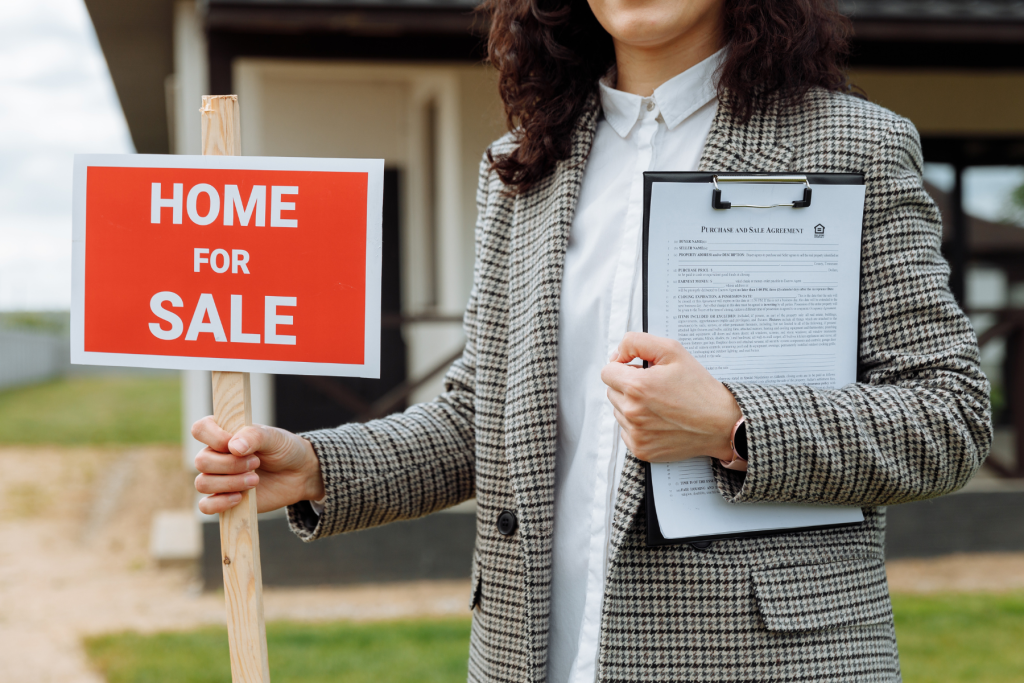 Woman holding a Home For Sale banner with Sale and Purchase Agreement of the real estate