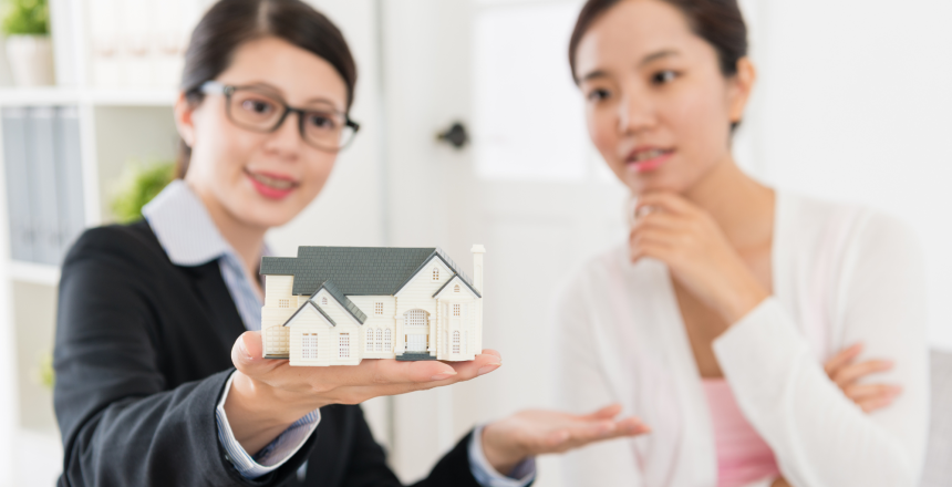 Mortgage broker presenting a miniature house model to a young property investor buying an investment property
