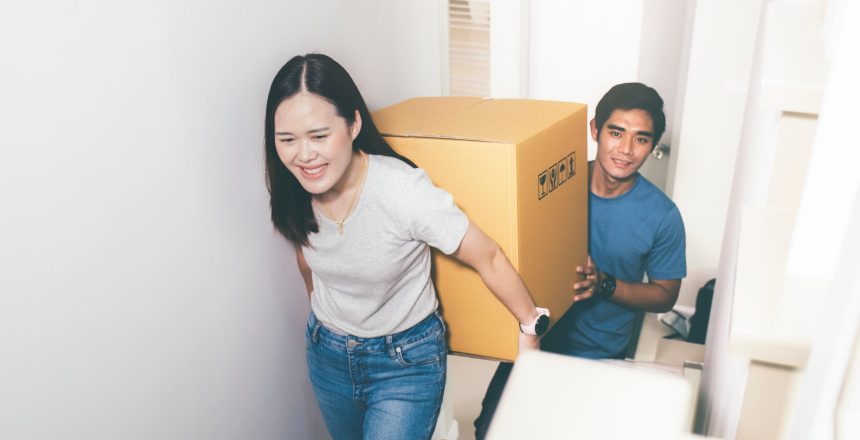 Young couple qualified for the First Home Buyer Choice and now is carrying a box to move in their new home